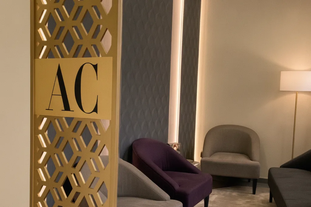 Sala d’espera d’AURA Clinics, amb butaques de vellut al costat de la gelosia daurada del monograma AC