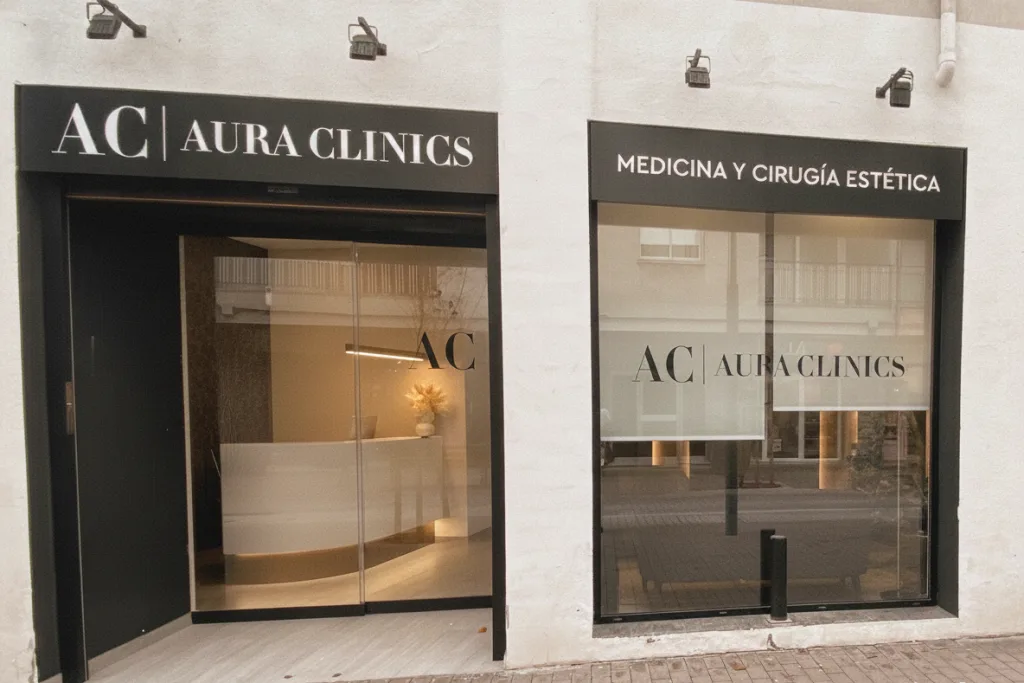 Façana d’AURA Clinics: rètol negre sobre la porta de vidre, a Carrer de Ramon Casas, 4
